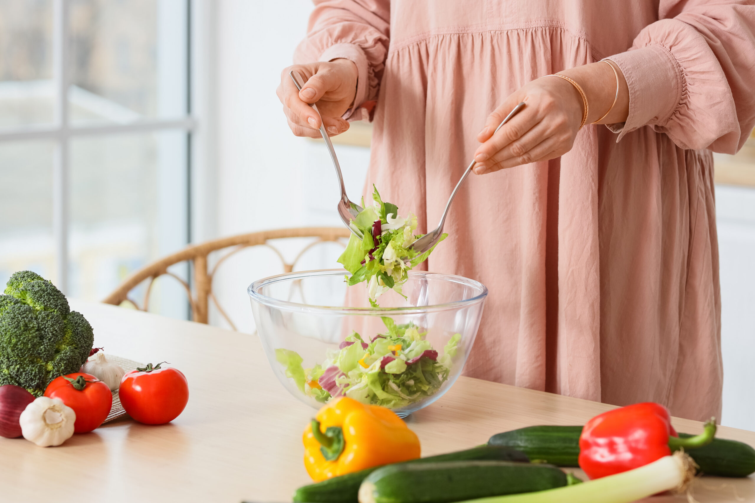 Woman preparing a fresh vegetable meal in her kitchen as part of a personalized nutrition plan