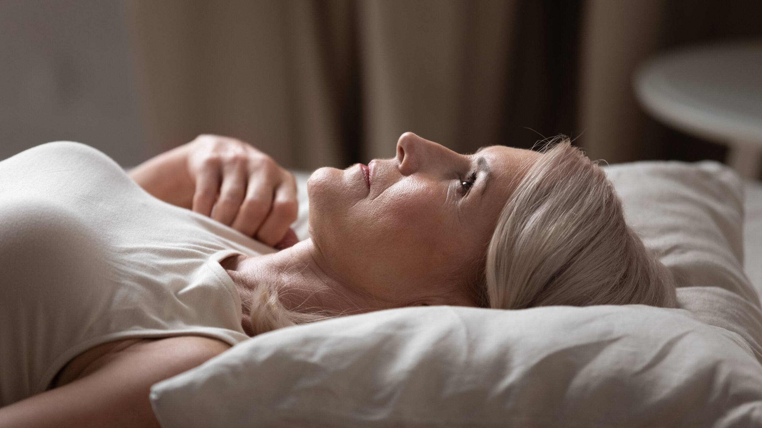 Woman lying awake at night, a sign of a nervous system stuck in survival mode