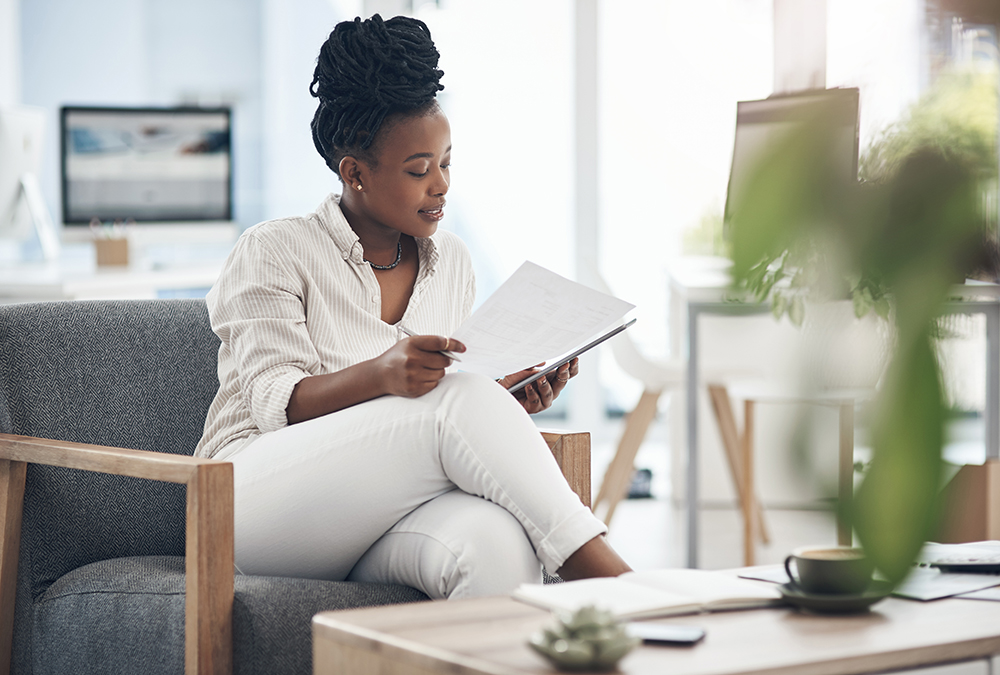 Shot of a businesswoman using her digital tablet while reading paperwork.